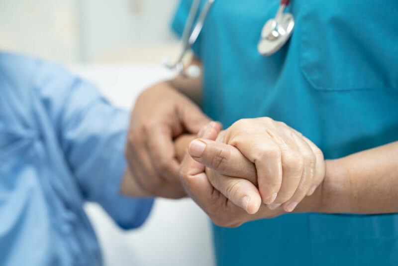 Doctor compassionately holding a patients hand